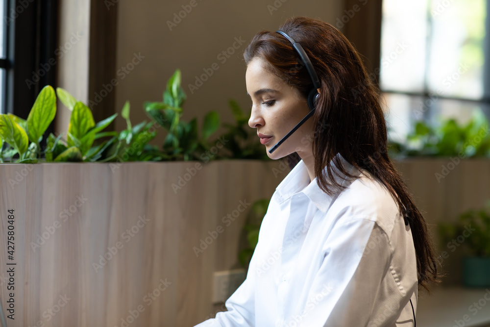 Attractive business woman Asian in suits and headsets are smiling while working with computer at office. Customer service assistant working in office. VOIP Helpdesk headset