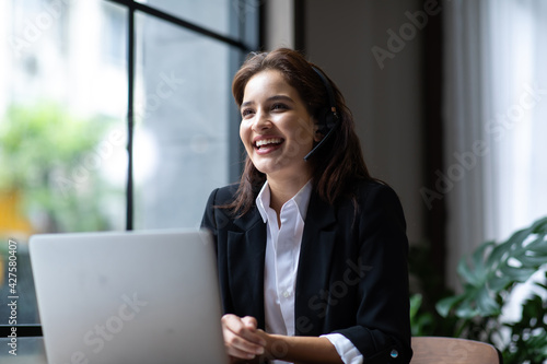 Attractive business woman Asian in suits and headsets are smiling while working with computer at office. Customer service assistant working in office. VOIP Helpdesk headset photo