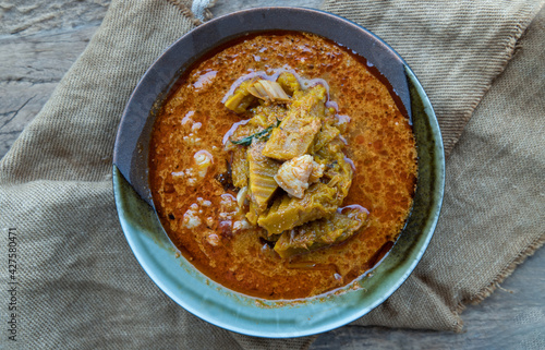 Thai red curry soup with Pumpkin, Pork and thai herb ingredient (curry made from coconut milk) in ceramic bowl. Top view, Selective focus.