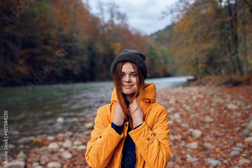 woman walks in the autumn forest in a yellow jacket mountains travel