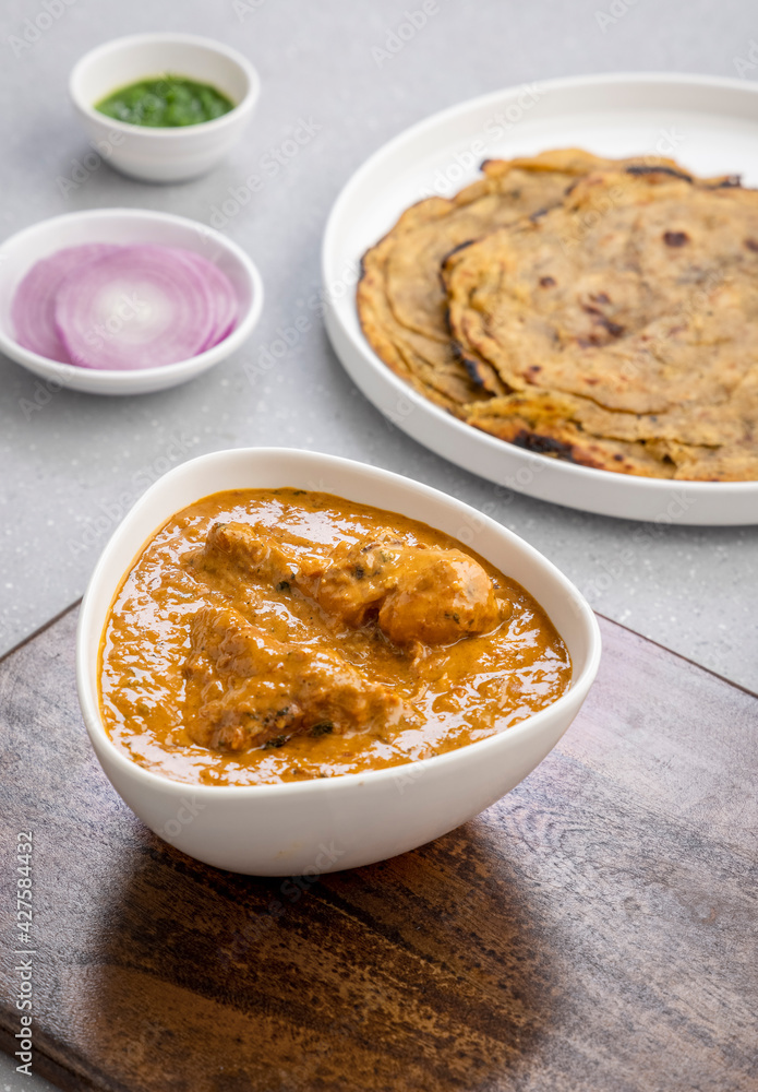 butter chicken, an Indian creamy chicken gravy served in a white bowl with roti or naan