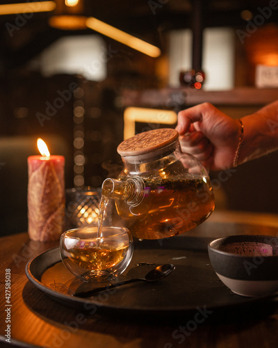 Tea brewing process, tea ceremony, freshly brewed red tea cup, warm soft light, dark background.