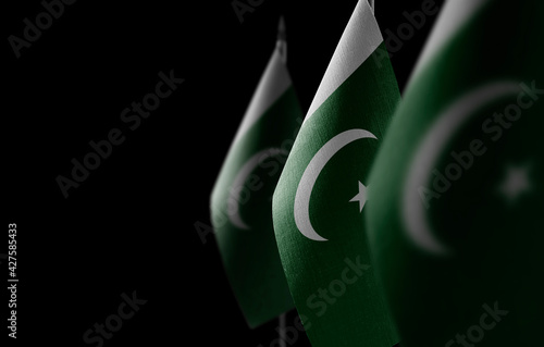 Small national flags of the Pakistan on a black background