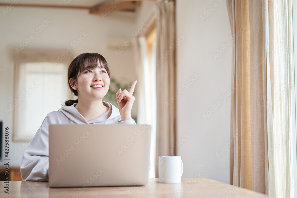 リビングで笑顔でパソコン操作をするアジア人女性 リビングで笑顔でパソコン操作をするアジア人女性