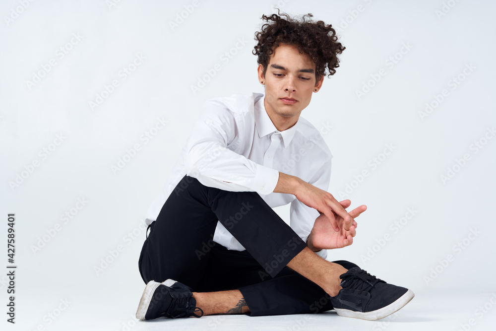 teenager in sneakers, black trousers and a white shirt In a bright room in full growth teenager in sneakers, black trousers and a white shirt In a bright room in full growth