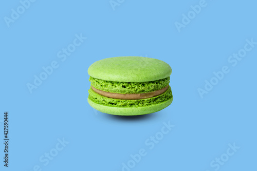 green macaron isolated on a pastel blue background. with a shadow photo