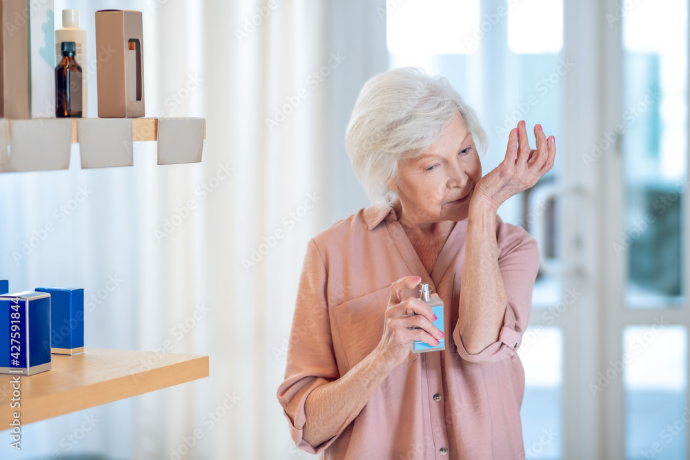 Gray-haired woman testing perfumes in a beauty shop Gray-haired woman testing perfumes in a beauty shop