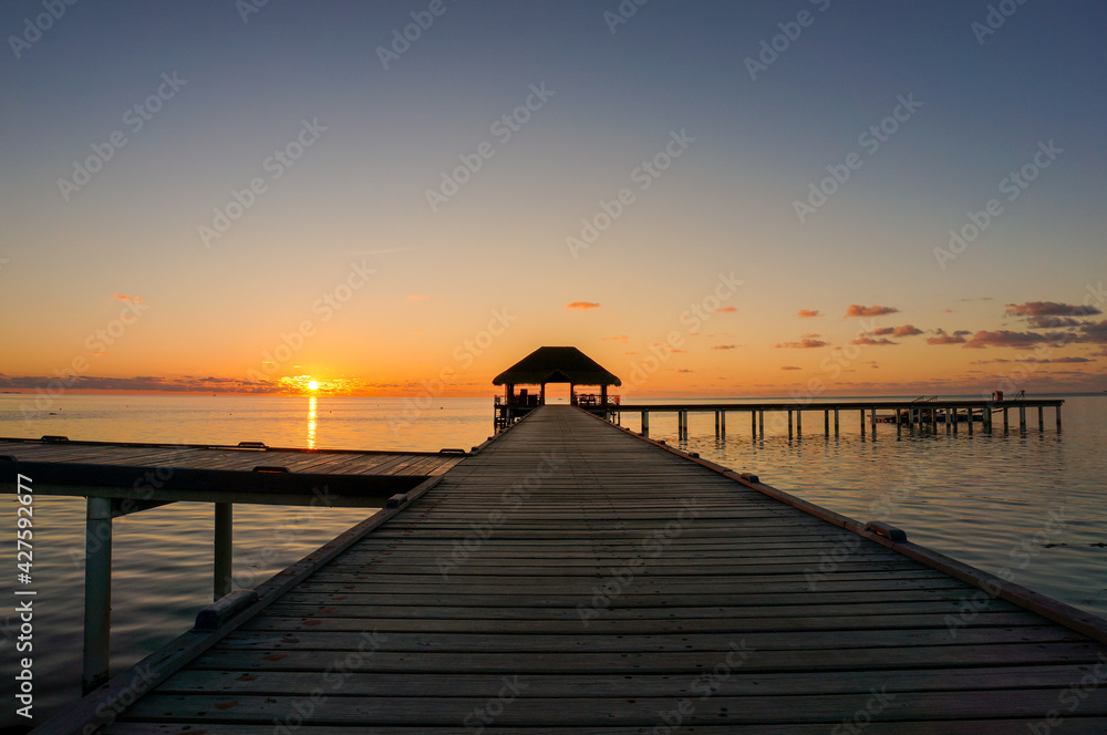 Wooden pier leading hut on indian ocean in the Maldives at sunset.Beautiful sky and clouds and beach background for summer vacation holiday and travel concept 
