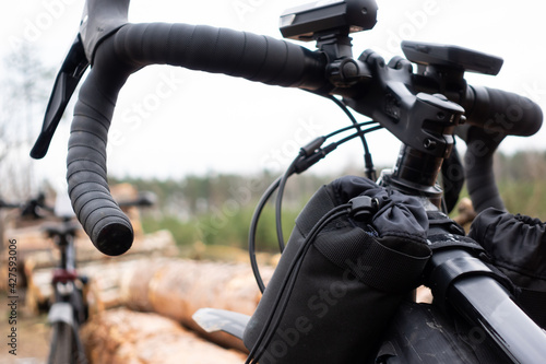 Adventure on a gravel bike in the woods. View of the bicycle handlebar with accessories. Taken under cloudy skies