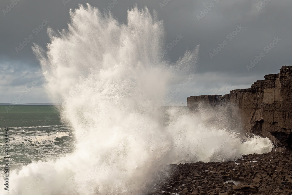 Power full ocean wave breaks on rock shore line creating big splash of water. Storm on West coast of Ireland. Power of Nature concept.