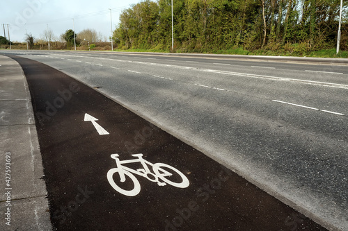 White bike sign on a asphalt on a separate lane for cycling by a motorway. Nobody