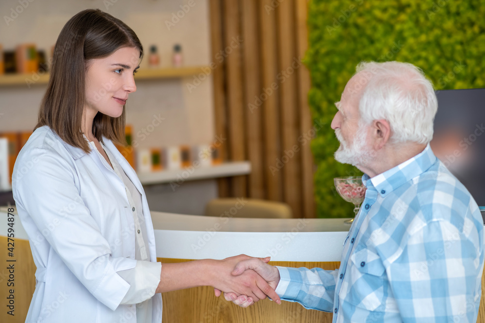 Fototapeta premium Cosmetologist in a white coat meeting a male customer