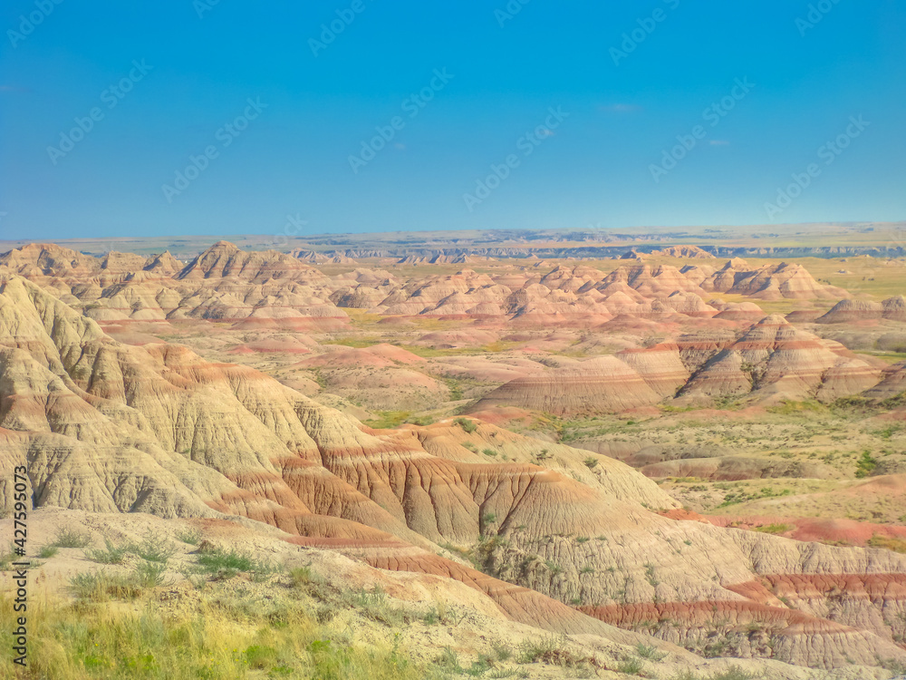 Surreal desert landscape of rugged pinnacles at Badlands National Park in South Dakota, United States. American travel destination. Aerial view. Blue sky in a sunny day. Copy space.