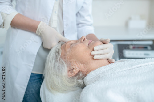 Mature woman enjoying face massage and looking relaxed