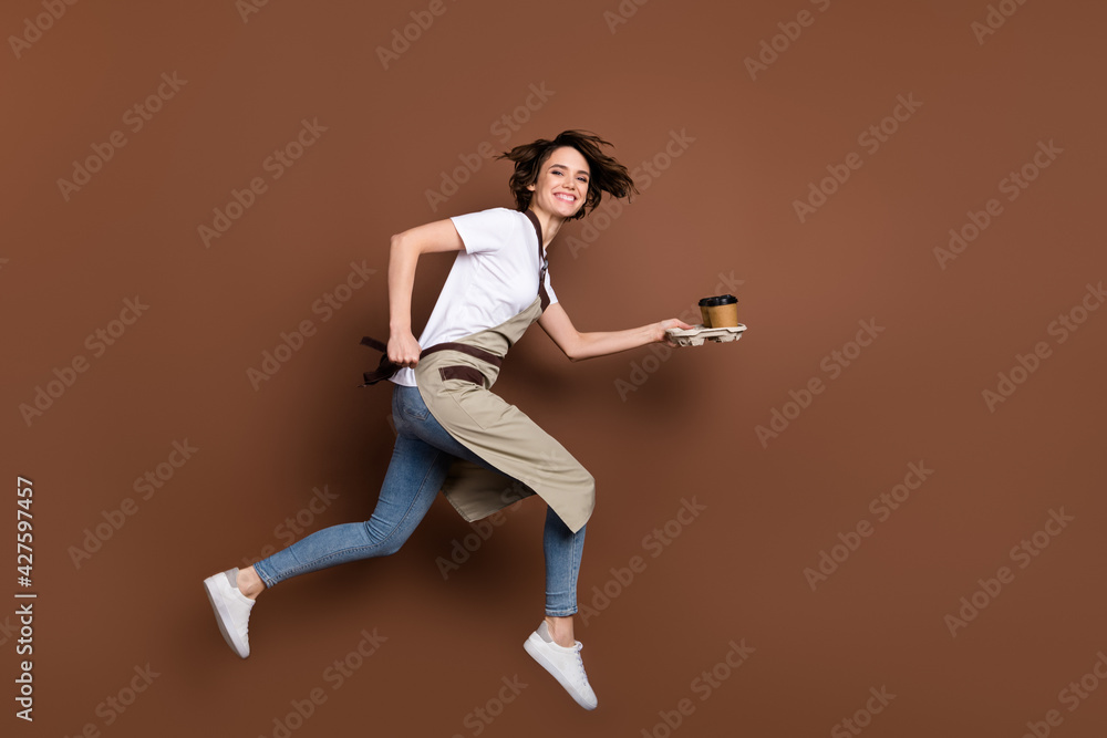 Full length body size view of attractive cheerful girl bringing coffee jumping fast service isolated over brown color background