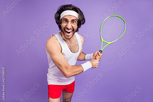 Photo of guy hold racket open mouth crazy face wear headband sportswear spectacles isolated violet background © deagreez