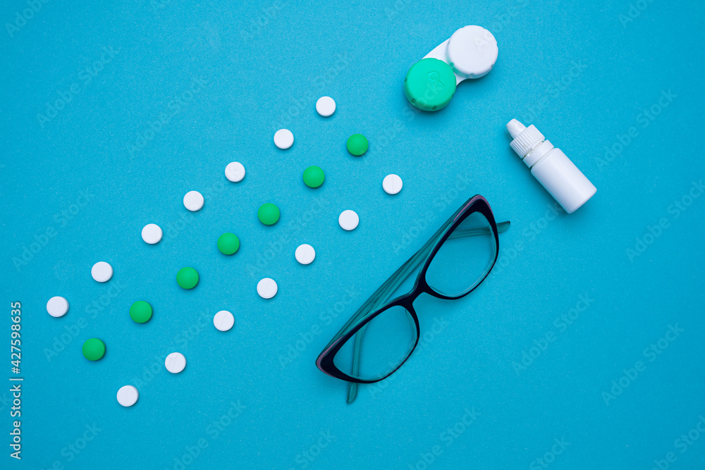 Flat lay Items for improving vision, tablets and vitamins, eye drops, contact lenses, glasses for improving vision on a blue background. Doctor's table. Eye and vision treatment concept. top view. Flat lay Items for improving vision, tablets and vitamins, eye drops, contact lenses, glasses for improving vision on a blue background. Doctor's table. Eye and vision treatment concept. top view.