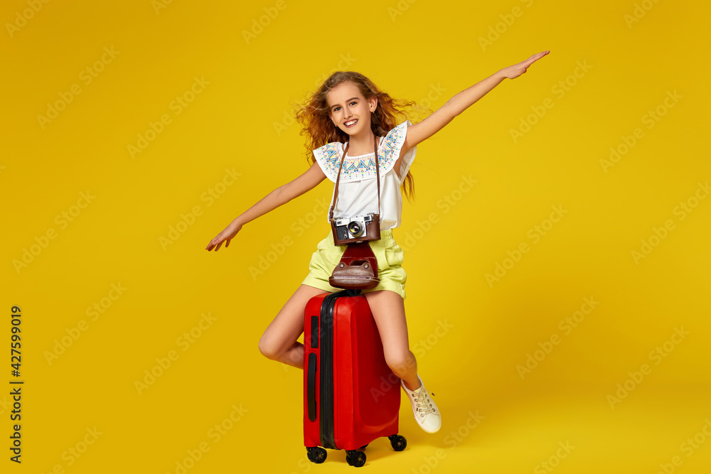 girl with retro vintage photo camera sitting on red suitcase