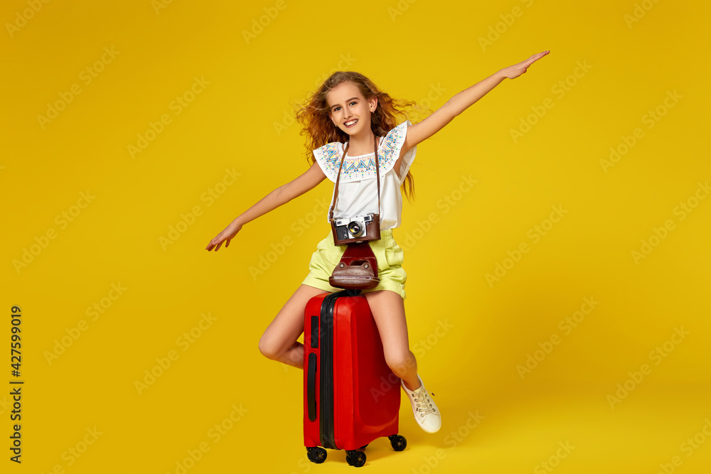 Fototapeta premium girl with retro vintage photo camera sitting on red suitcase