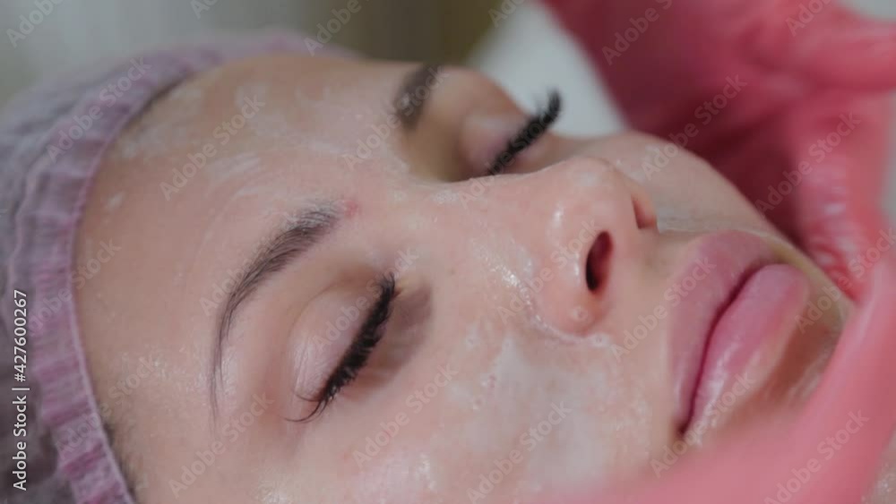 Professional beautician rubs liquid soap on a woman's face. Professional beautician rubs liquid soap on a woman's face.