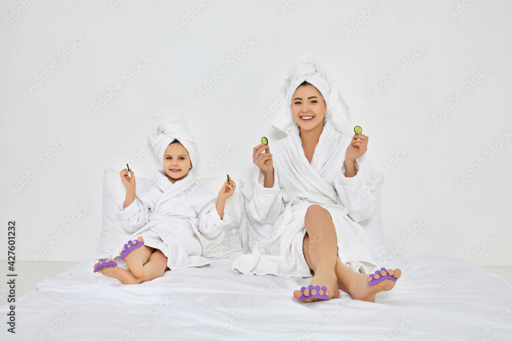 happy woman and little daughter holding fresh cucumber slices happy woman and little daughter holding fresh cucumber slices