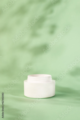 White moisturizer cream, shadow play on mint background. Cream container mockup. Blank Cosmetics jar, packaging design. Skincare and body care concept.