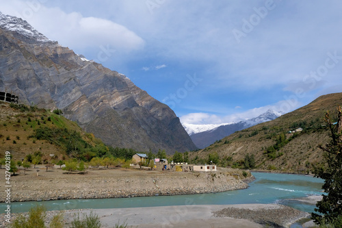 Fototapeta Naklejka Na Ścianę i Meble -  A cozy little village on the banks of a turquoise river in the mountains of the Himalayas on a clear autumn day