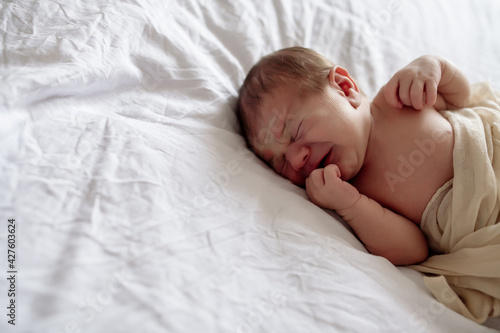 Little newborn baby sleeping on the bed in the bedroom, lulled by mom
