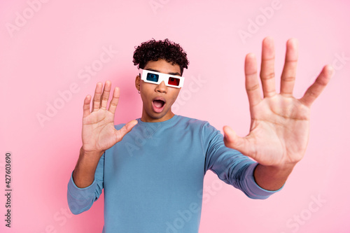 Photo portrait of young guy watching film in cinema wearing 3d glasses eating pop corn smiling isolated on pastel pink color background © deagreez