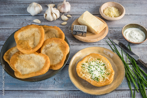 Traditional Hungarian Langos with garlic, cheese and sour cream, garnished with chopped chives photo