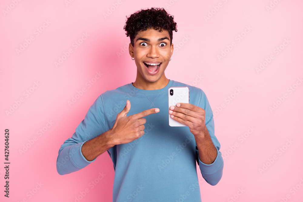 Photo of impressed nice brunet guy point telephone wear blue sweater isolated on pastel pink color background Photo of impressed nice brunet guy point telephone wear blue sweater isolated on pastel pink color background