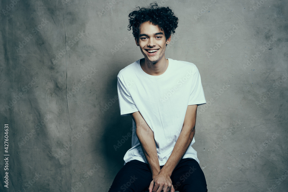 happy curly guy in a t-shirt gesturing with his hands on a fabric background in a studio photoshoot model happy curly guy in a t-shirt gesturing with his hands on a fabric background in a studio photoshoot model