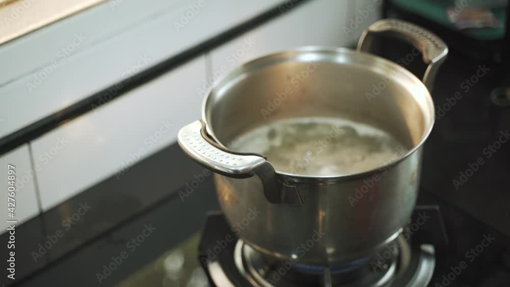 Boiling hot water soup in stainless steel pot over gas stove Boiling hot water soup in stainless steel pot over gas stove