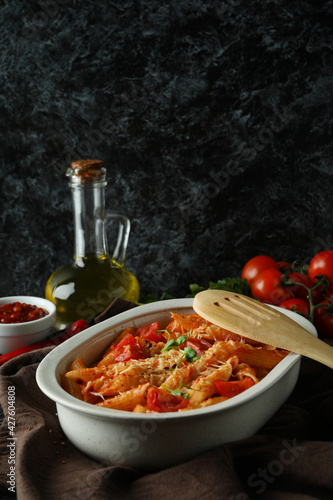 Tray with pasta with tomato sauce against black smokey background
