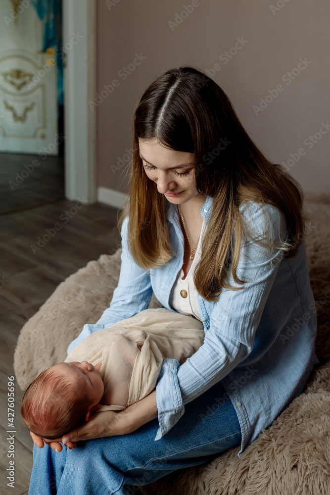 Young beautiful mother with long hair holds a newborn baby son in her arms
Young beautiful mother with long hair holds a newborn baby son in her arms