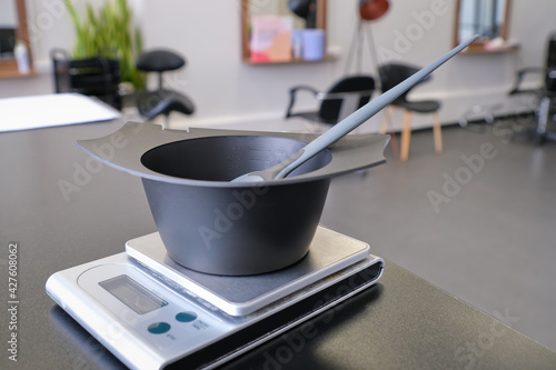 Mixing bowl and hair dye brush on electronic scale. Hair dye measuring and mixing kit. Hair coloring tools set. Professional instrument for hair colorist and hairstylist.