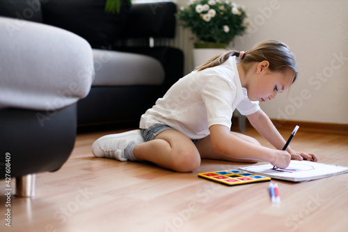 Little girl drawing and sitting on the floor