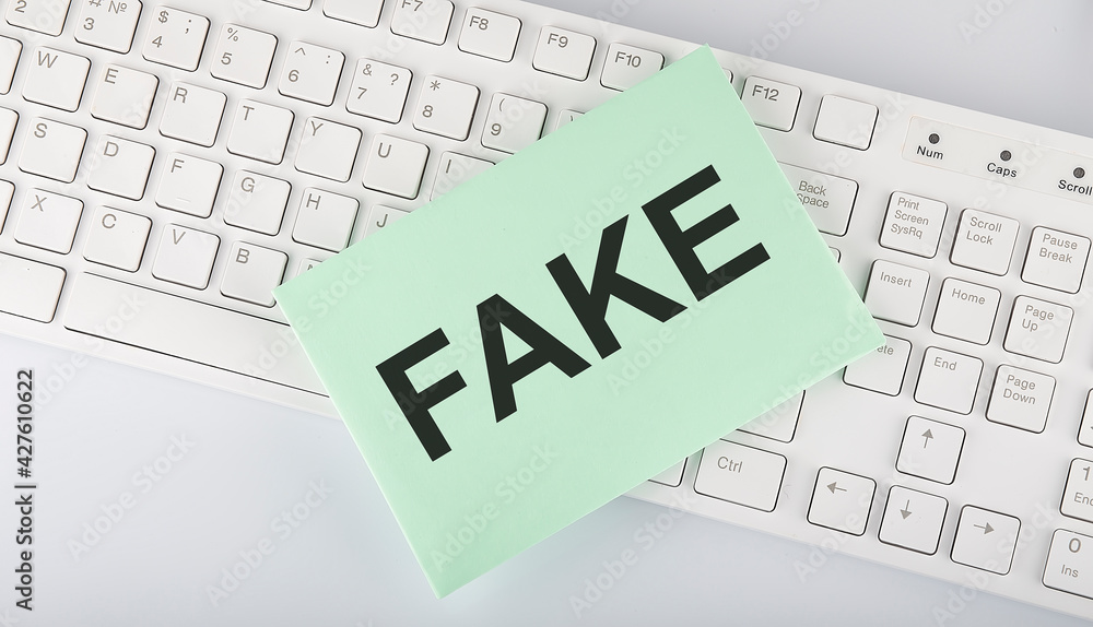 text FAKE on envelope on keyboard on the white background text FAKE on envelope on keyboard on the white background
