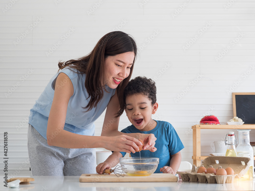 Mother and cute toddler son preparing breakfast in the kitchen at home. Happy family lifestyle, Mother's day concept. Mother and cute toddler son preparing breakfast in the kitchen at home. Happy family lifestyle, Mother's day concept.