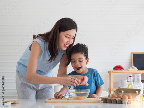 Mother and cute toddler son preparing breakfast in the kitchen at home. Happy family lifestyle, Mother's day concept.