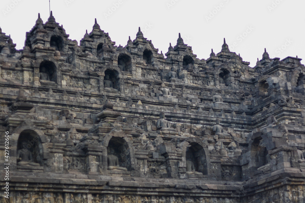Detail of exterior wall of ancient Borobudur temple with meditating Buddha statues. No people. Popular tourist and Buddhist pilgrimage destination.