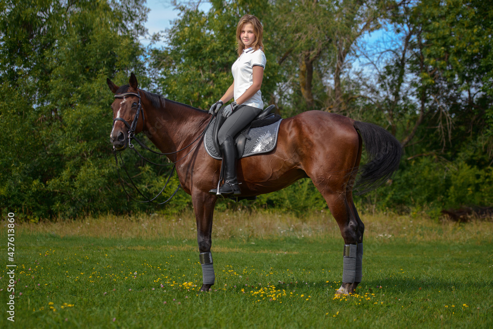 A girl rider trains riding a horse on a spring day. A girl rider trains riding a horse on a spring day.