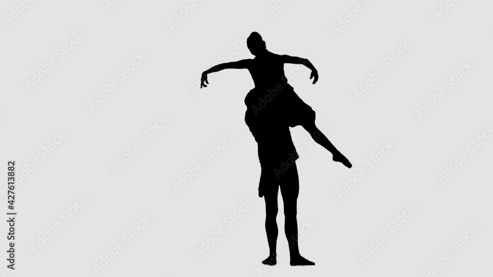 Silhouette professional ballet pair practicing moves on dark stage. Gracefulness and tenderness in every movement. Silhouette professional ballet pair practicing moves on dark stage. Gracefulness and tenderness in every movement.