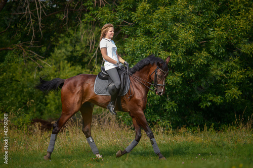 A girl rider trains riding a horse on a spring day. © sheikoevgeniya