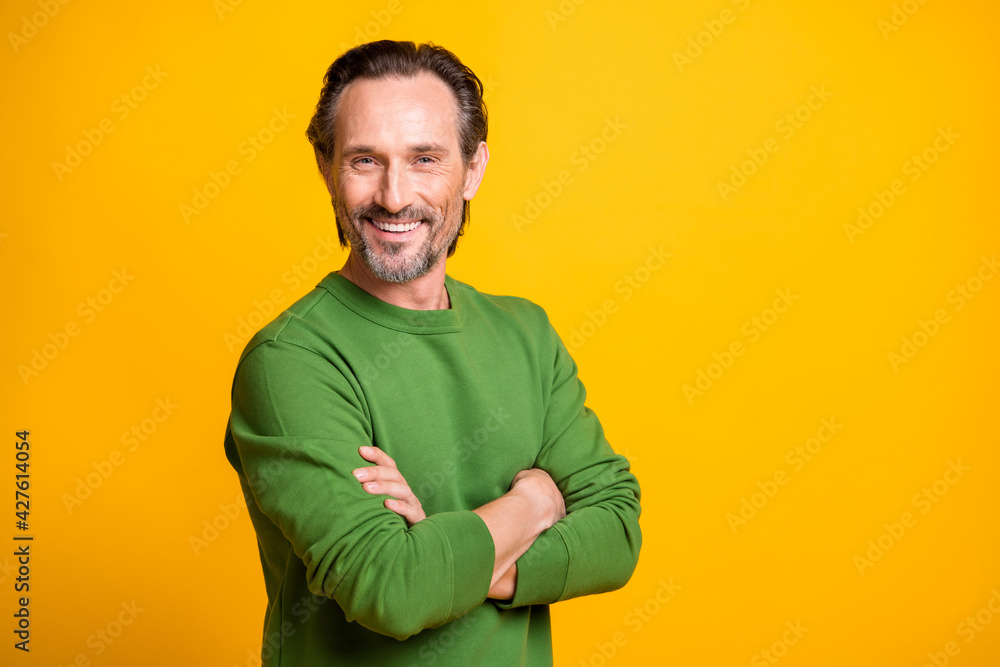 Photo of positive man folded arms camera beaming smile wear green sweater isolated yellow color background Photo of positive man folded arms camera beaming smile wear green sweater isolated yellow color background