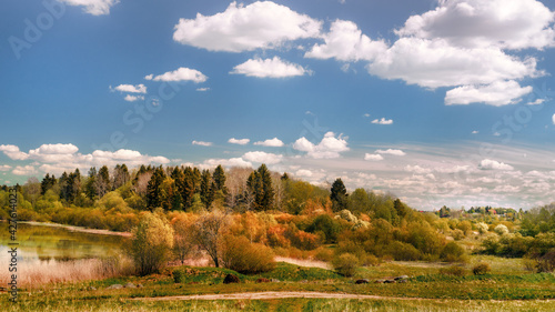 Wide angle panoramic view on lake, wooded hill and small village in autumn colors