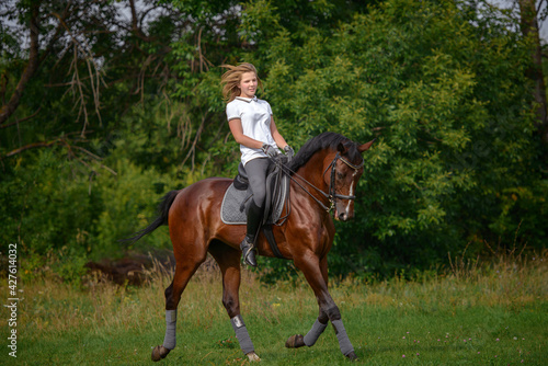 A girl rider trains riding a horse on a spring day.