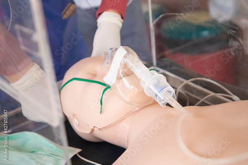 Photography Closeup of hand putting nebulizer mask to manikin via plastic box
