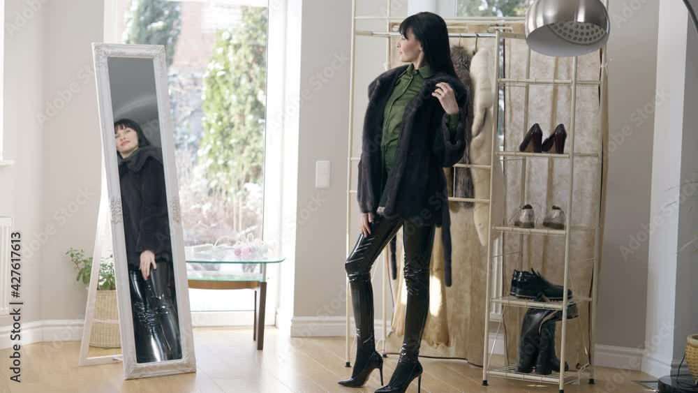 Stylish young slim woman in leather pants, high-heels and fur coat spinning in front of mirror indoors. Wide shot of confident gorgeous Caucasian lady choosing outfit in the morning at home Stylish young slim woman in leather pants, high-heels and fur coat spinning in front of mirror indoors. Wide shot of confident gorgeous Caucasian lady choosing outfit in the morning at home