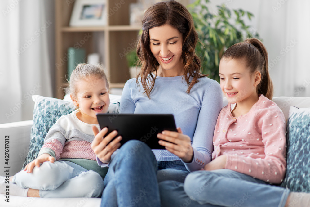 people, family and technology concept - happy mother and two daughters with tablet pc computer at home people, family and technology concept - happy mother and two daughters with tablet pc computer at home